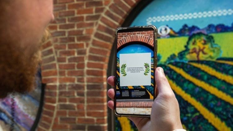 Someone reading information on an art installation through an augmented reality app