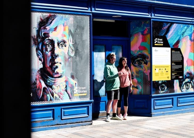 Artist Michael Corr and his loved one standing in front of his painting in a vacant shop unit