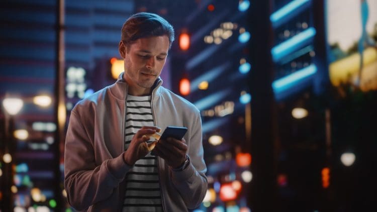 Man in a nighttime city using phone to get directions