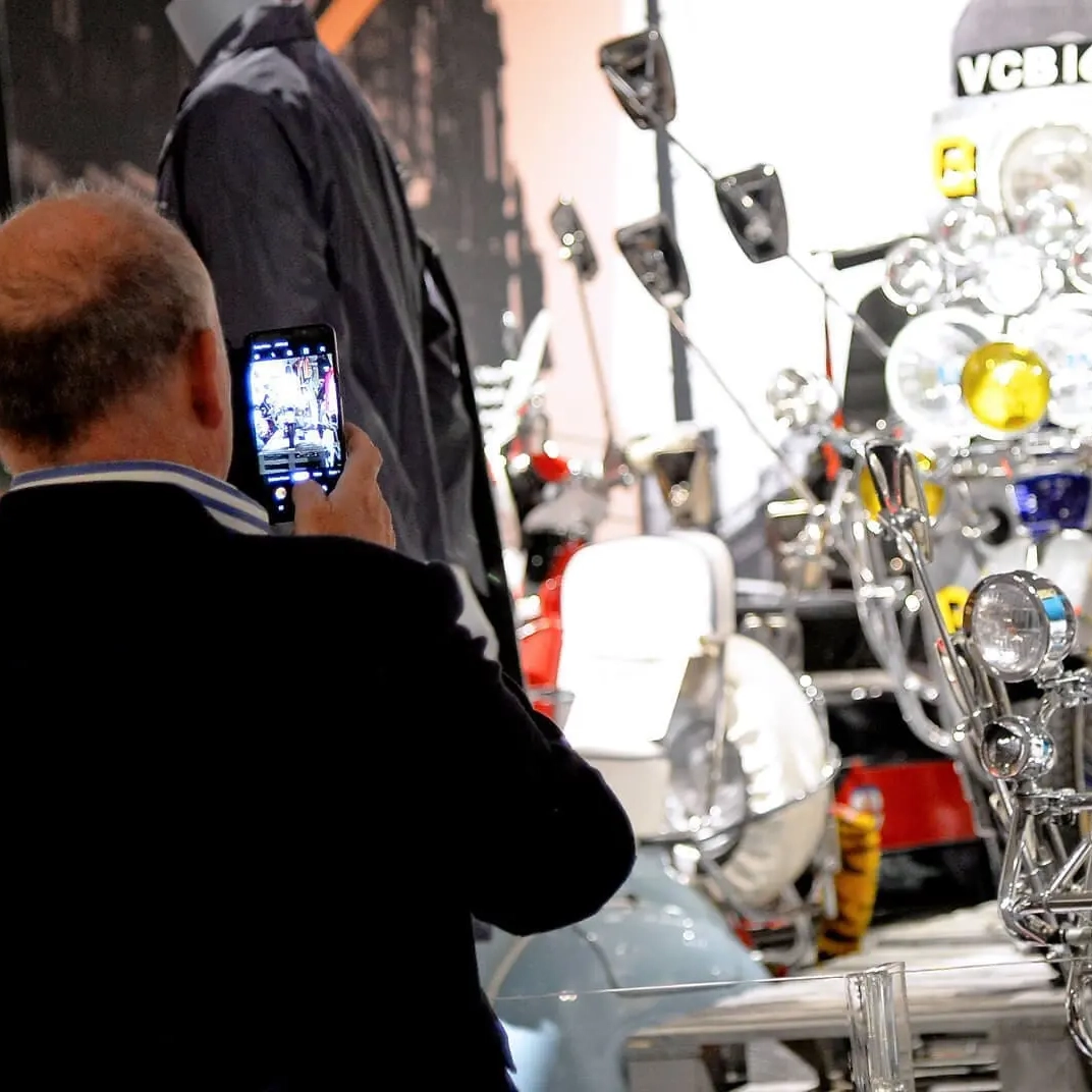 Man using mobile to take photo of display at MODS: Shaping a Generation Exhibition