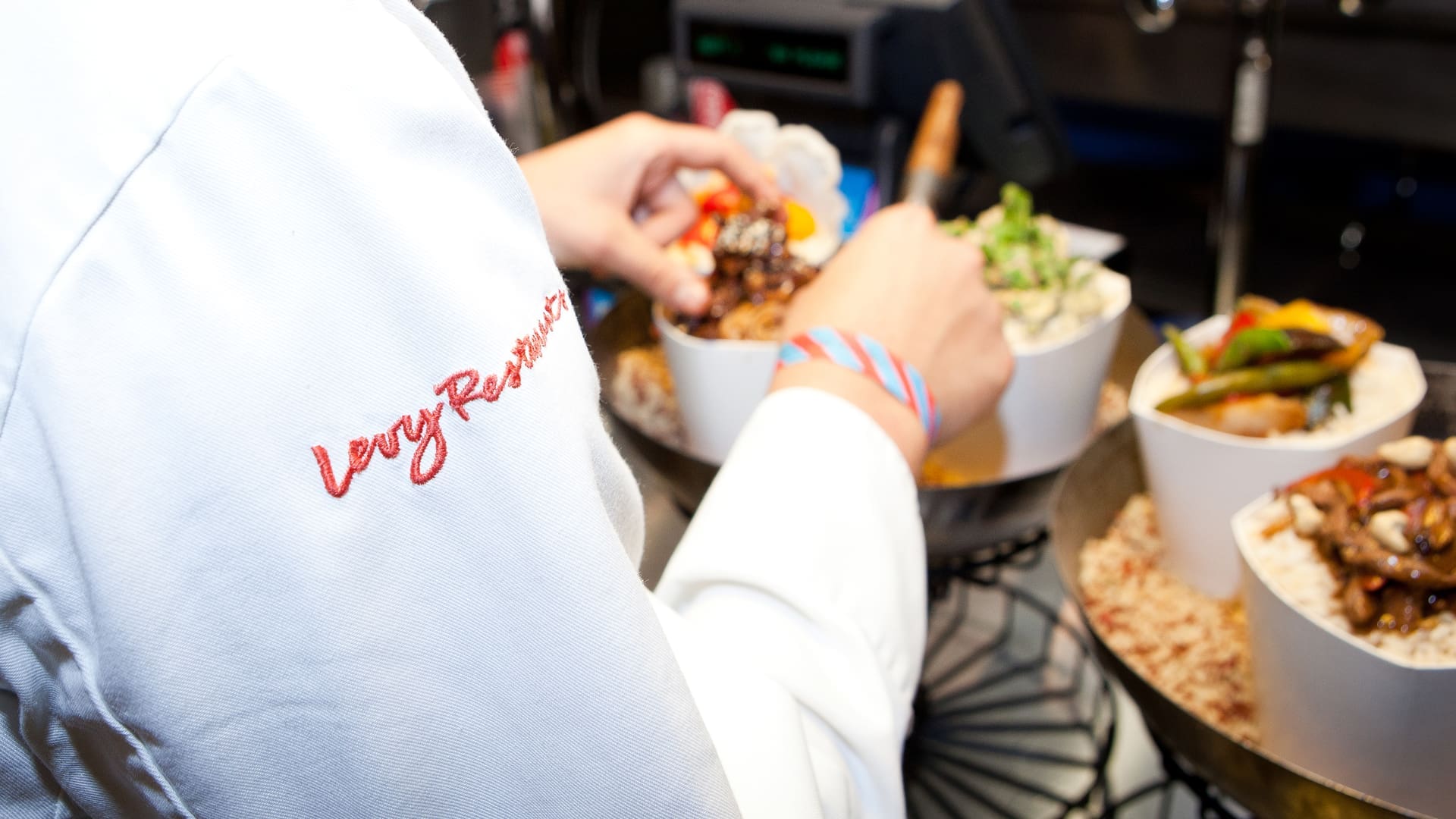 Chef at Levy Restaurants putting finishing touches on a dish of stir fry