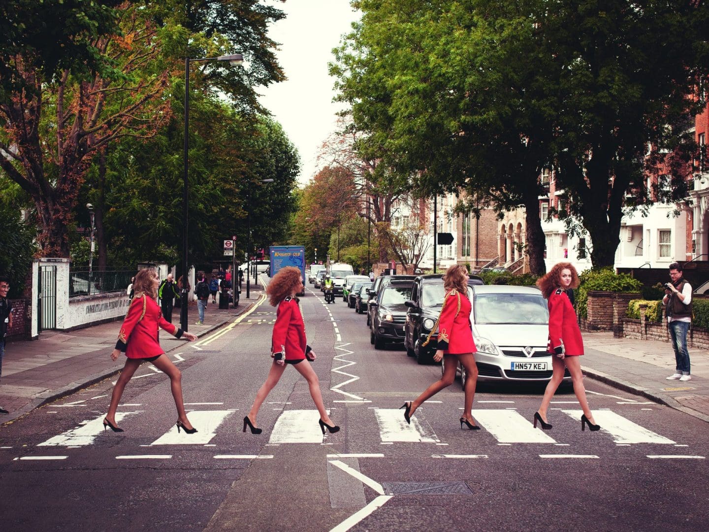 Four women wearing red jackets walking across the famous Abbey Road crossing